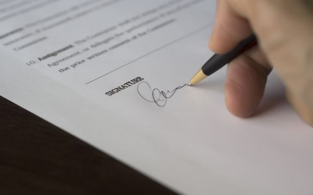 A hand signing a contract