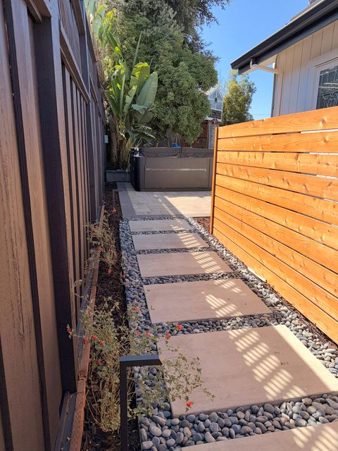 Stepping-stone side-yard walkway beside a horizontal wood-slat privacy screen