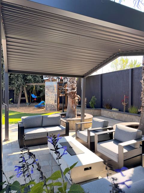 Outdoor lounge with sofas and a fire table under a louvered pergola