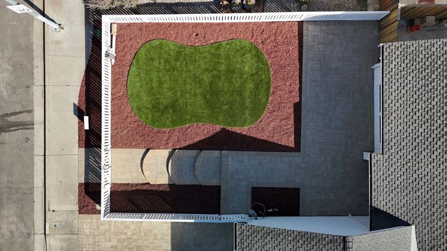 Top-down view of the fenced front yard with artificial turf and paver steps
